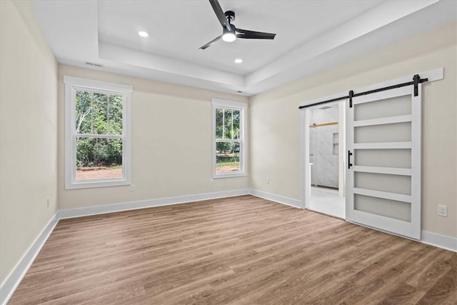 711 Concord Rd, Anderson, SC 29621 - unfurnished bedroom featuring a barn door, wood finished floors, multiple windows, a raised ceiling, and recessed lighting