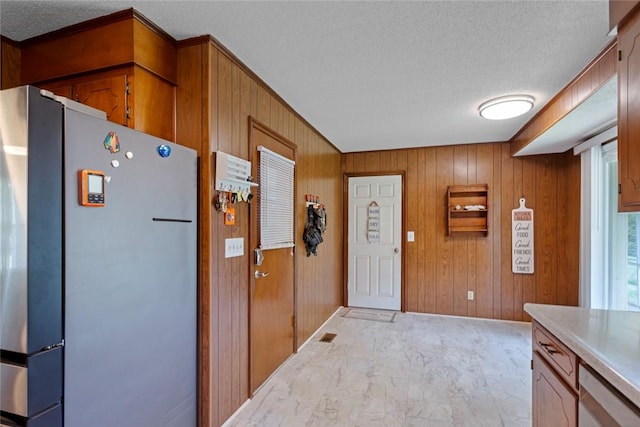 123 Radisson Rd, Seneca, SC 29678 - kitchen with freestanding refrigerator, a textured ceiling, wooden walls, brown cabinetry, and light countertops