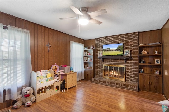 123 Radisson Rd, Seneca, SC 29678 - living area featuring a brick fireplace, a ceiling fan, light wood finished floors, a textured ceiling, and wooden walls