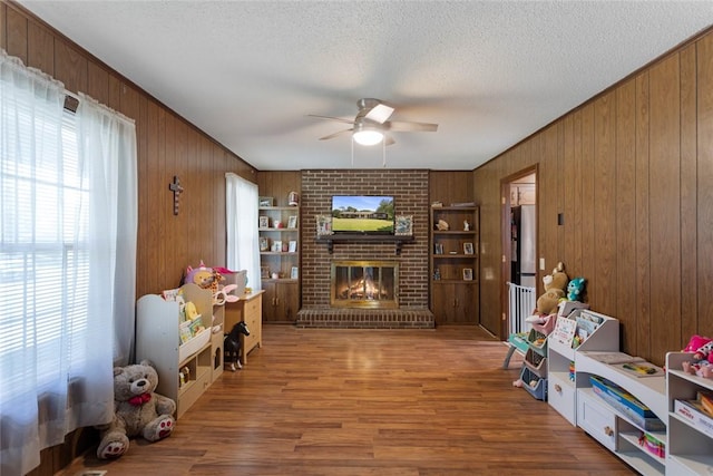 123 Radisson Rd, Seneca, SC 29678 - living area featuring a brick fireplace, a ceiling fan, wooden walls, wood finished floors, and a textured ceiling