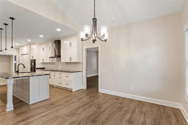 340 Fiddlers Way, Seneca, SC 29678 - kitchen featuring wall chimney range hood, wood finished floors, a chandelier, white cabinets, and dark stone counters