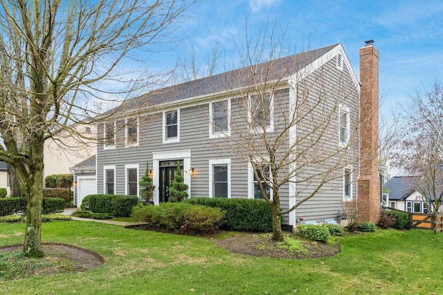 colonial-style house featuring a garage and a front lawn