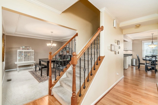 staircase with hardwood / wood-style flooring, crown molding, and a chandelier