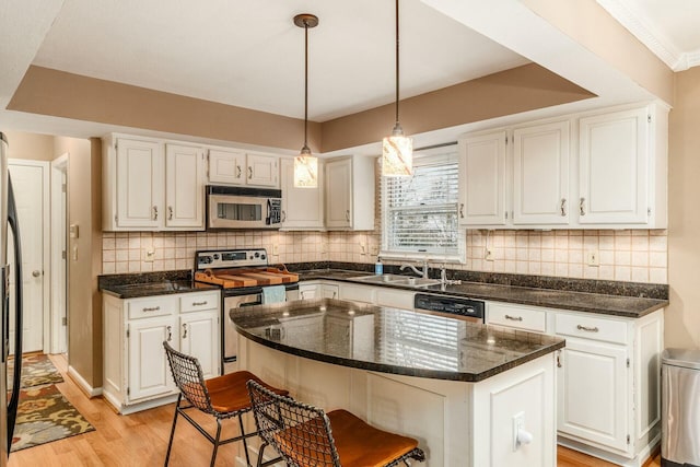 kitchen with white cabinets, a kitchen island, stainless steel appliances, and decorative light fixtures