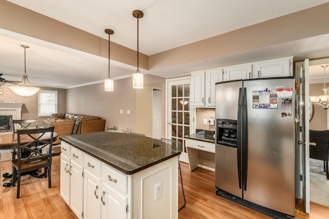 kitchen featuring a kitchen island, decorative light fixtures, stainless steel fridge with ice dispenser, white cabinetry, and a breakfast bar area