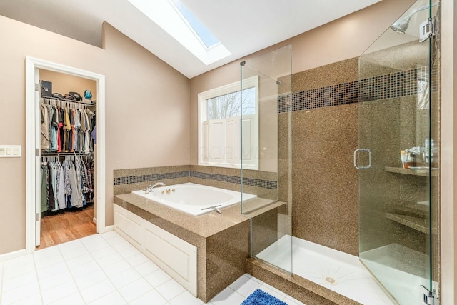 bathroom with vaulted ceiling with skylight, tile patterned flooring, and shower with separate bathtub