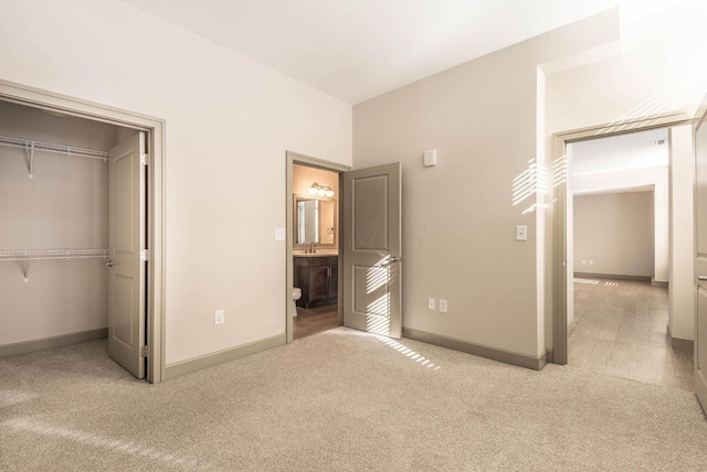 unfurnished bedroom with connected bathroom, light colored carpet, and a closet