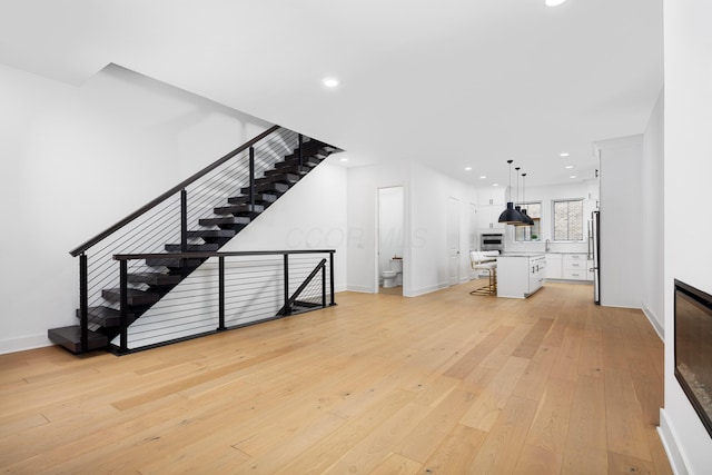 unfurnished living room featuring sink and light wood-type flooring