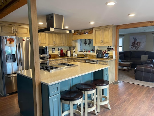 kitchen with appliances with stainless steel finishes, wall chimney range hood, dark hardwood / wood-style floors, a kitchen island, and a breakfast bar area