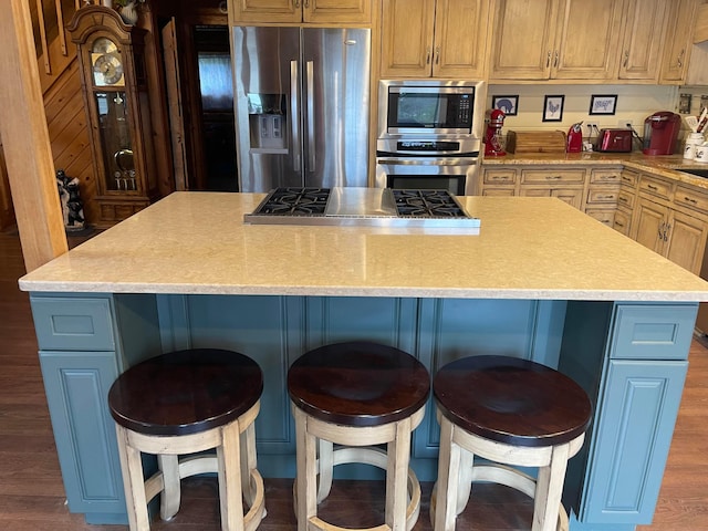 kitchen with hardwood / wood-style floors, a kitchen breakfast bar, a center island, and stainless steel appliances