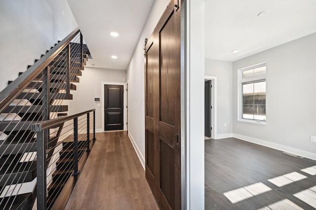 hallway with dark wood-type flooring and a barn door