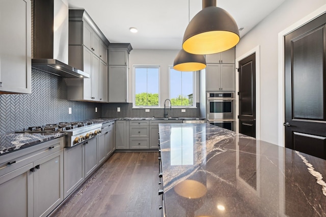 kitchen with gray cabinets, dark wood-type flooring, wall chimney exhaust hood, and pendant lighting