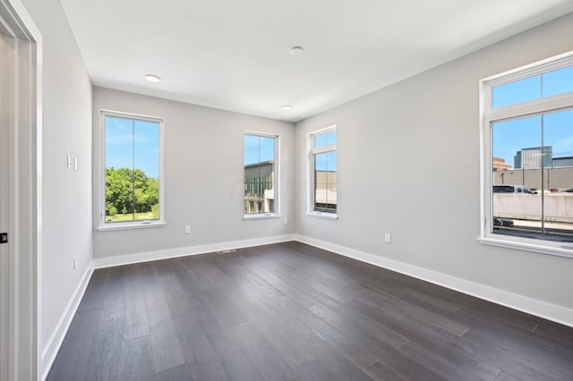 empty room featuring dark hardwood / wood-style flooring and a wealth of natural light