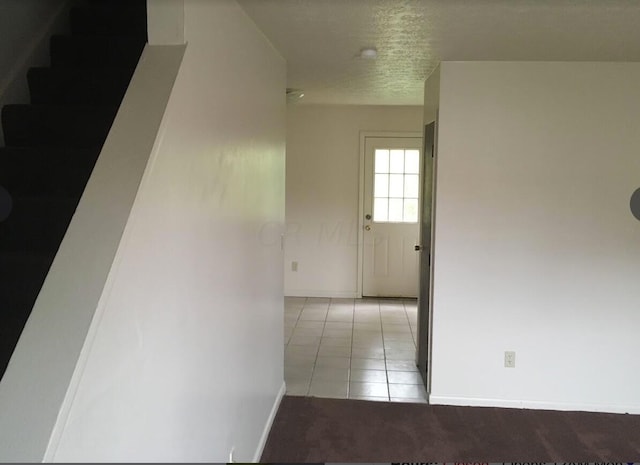 hallway featuring light tile patterned flooring and a textured ceiling