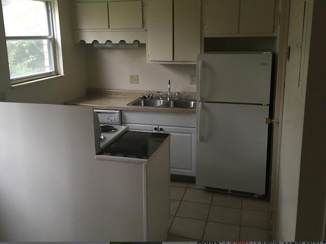 kitchen with white cabinets, light tile patterned floors, white refrigerator, and sink