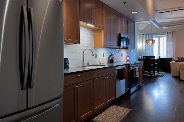 kitchen featuring dark hardwood / wood-style flooring, tasteful backsplash, stainless steel appliances, sink, and hanging light fixtures