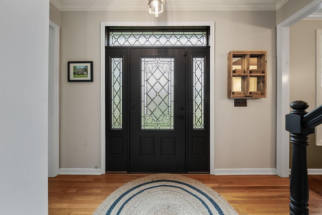 foyer featuring baseboards, ornamental molding, and wood finished floors