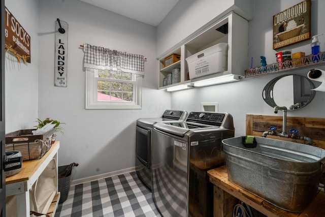 clothes washing area featuring baseboards, a sink, washer and dryer, and laundry area