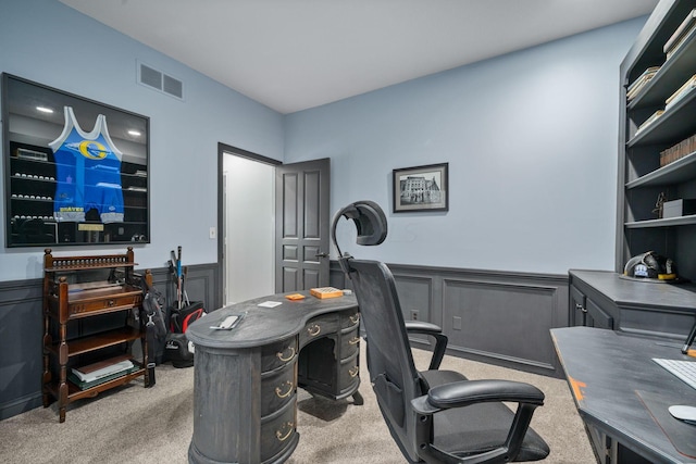 carpeted office featuring a wainscoted wall, visible vents, and a decorative wall