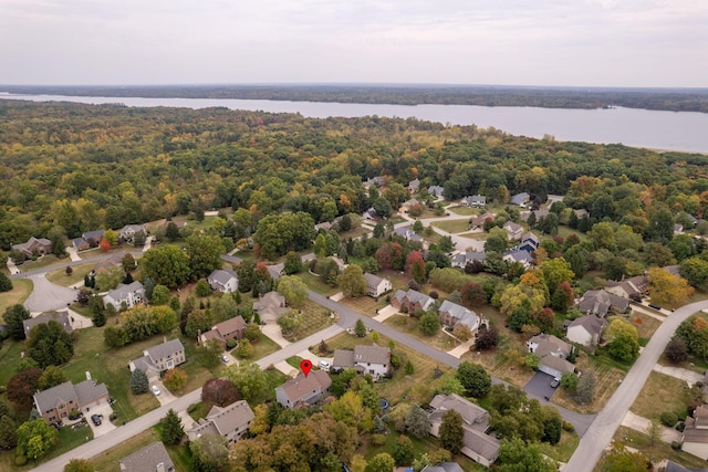drone / aerial view with a wooded view, a residential view, and a water view