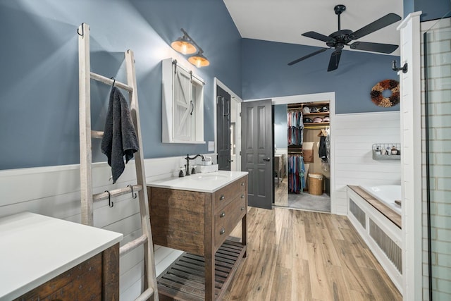 bathroom featuring wood finished floors, a shower, ceiling fan, vanity, and a walk in closet
