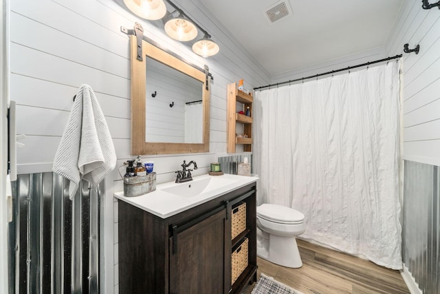 bathroom featuring wood walls, wood finished floors, visible vents, toilet, and vanity