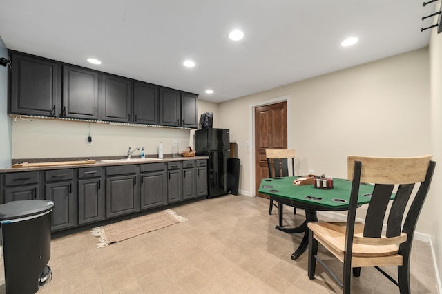 kitchen featuring recessed lighting, freestanding refrigerator, baseboards, and a sink