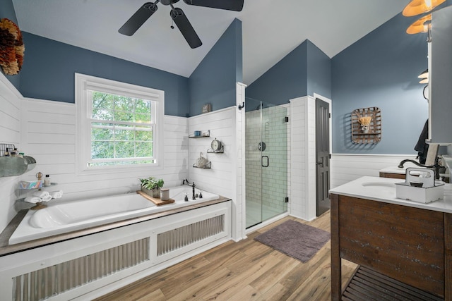 full bath with a wainscoted wall, a stall shower, a ceiling fan, wood finished floors, and a garden tub