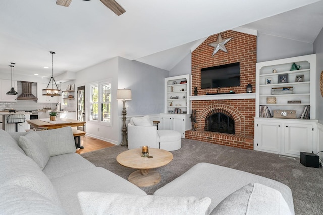 living area with ceiling fan with notable chandelier, vaulted ceiling, and a fireplace