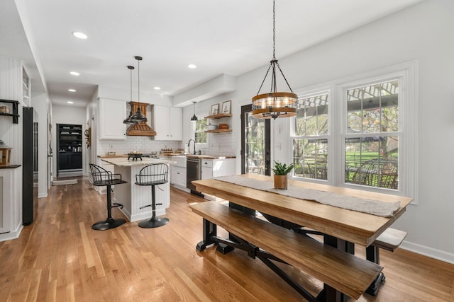 dining area featuring light wood-type flooring, a wealth of natural light, baseboards, and a notable chandelier