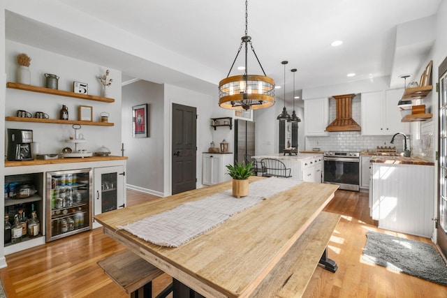 dining area with beverage cooler, a chandelier, light wood-type flooring, baseboards, and recessed lighting