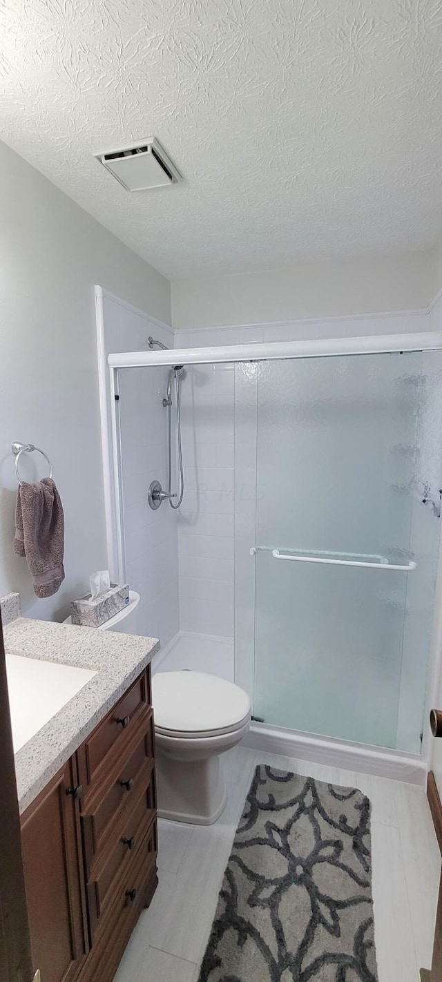 bathroom with vanity, an enclosed shower, a textured ceiling, and toilet