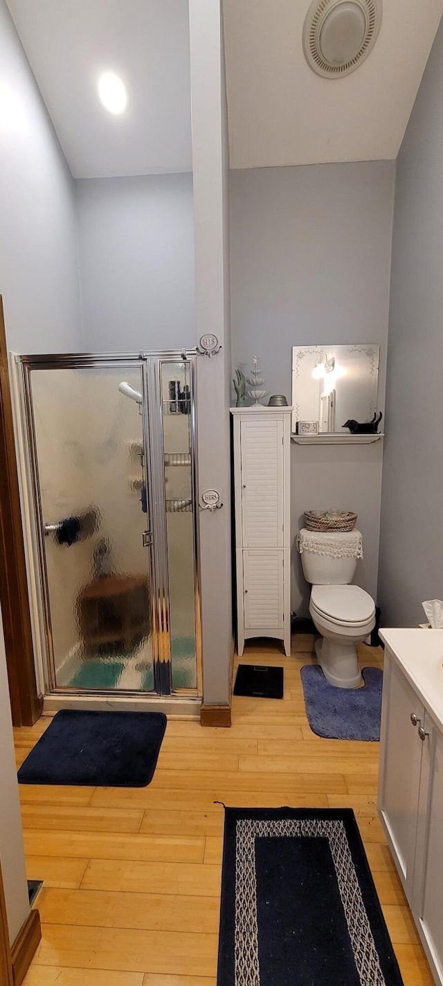 bathroom featuring wood-type flooring, vanity, toilet, and an enclosed shower