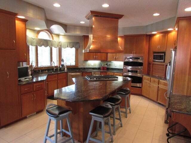 kitchen with premium range hood, a breakfast bar area, stainless steel appliances, a kitchen island, and sink