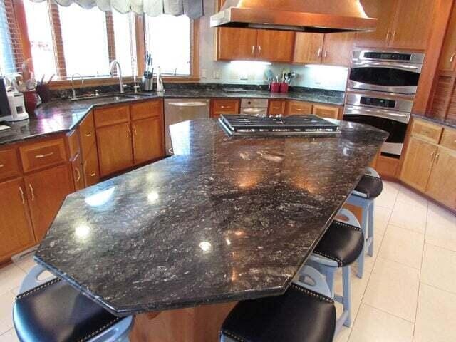 kitchen with appliances with stainless steel finishes, a kitchen bar, sink, a large island, and range hood