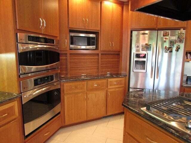 kitchen featuring light tile patterned floors, appliances with stainless steel finishes, and dark stone countertops