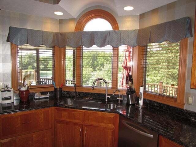 kitchen with stainless steel dishwasher, dark stone counters, and sink