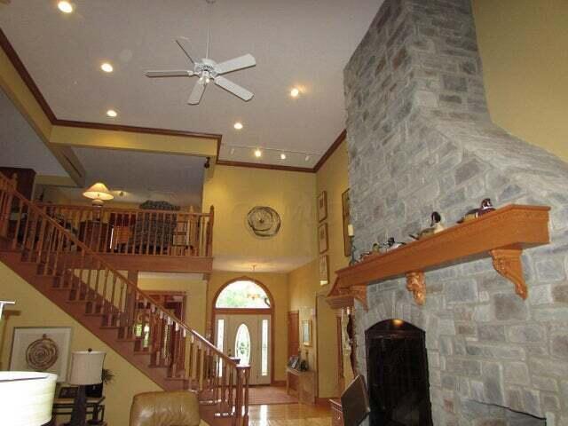 living room with a fireplace, ceiling fan, a towering ceiling, and ornamental molding