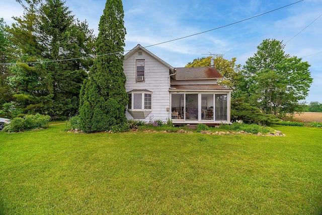 back of property featuring a sunroom and a lawn