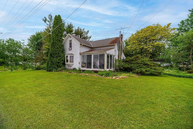 back of property featuring a lawn and a sunroom