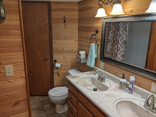 bathroom featuring tile patterned floors, vanity, wood walls, and toilet