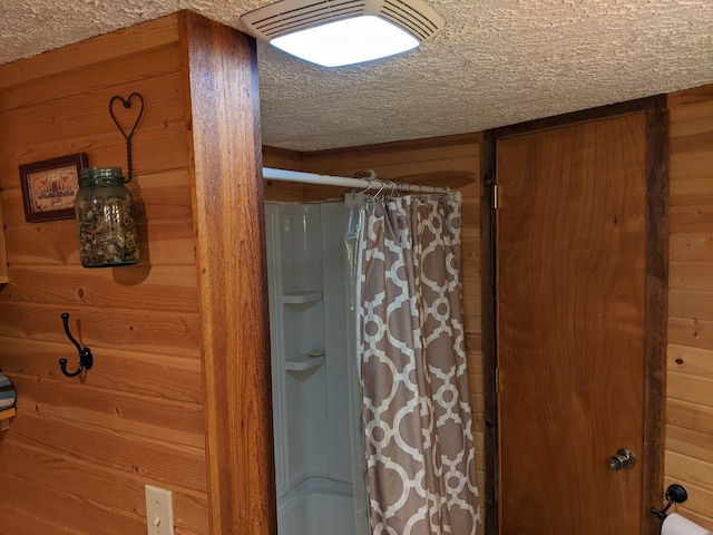 bathroom with a textured ceiling and wooden walls