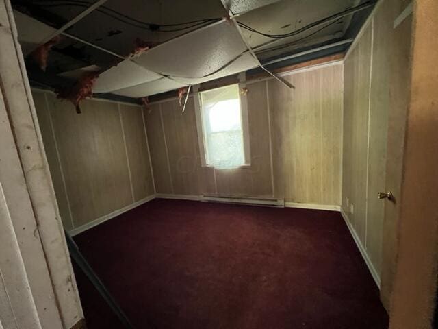 basement featuring dark carpet and a baseboard heating unit