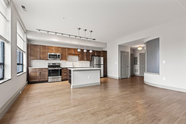 kitchen featuring a center island, hanging light fixtures, appliances with stainless steel finishes, tasteful backsplash, and light hardwood / wood-style floors