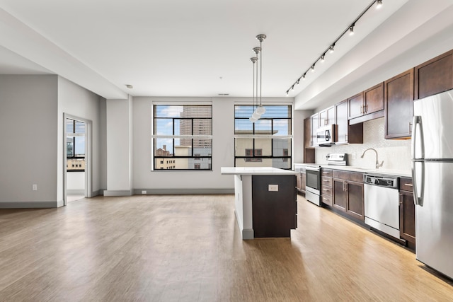 kitchen with pendant lighting, a center island, light hardwood / wood-style floors, and stainless steel appliances