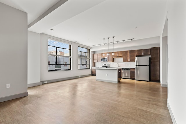 unfurnished living room with track lighting, sink, and light hardwood / wood-style flooring