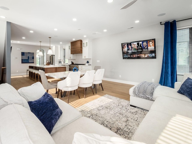 living room with a wealth of natural light, ceiling fan, and light hardwood / wood-style floors