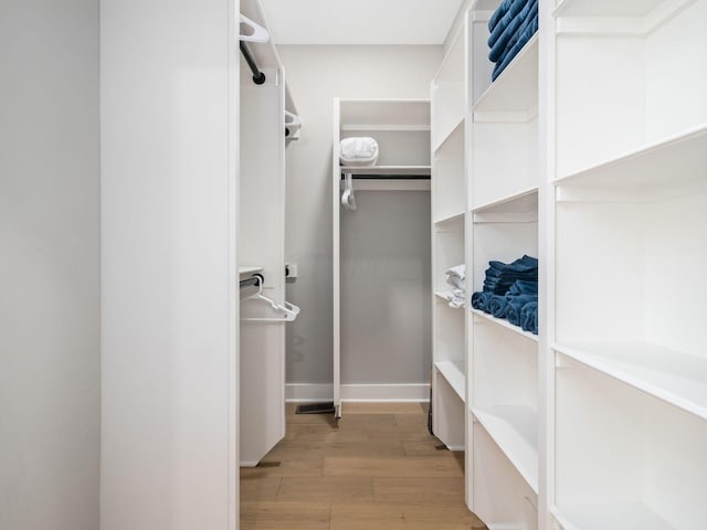 walk in closet with light hardwood / wood-style floors