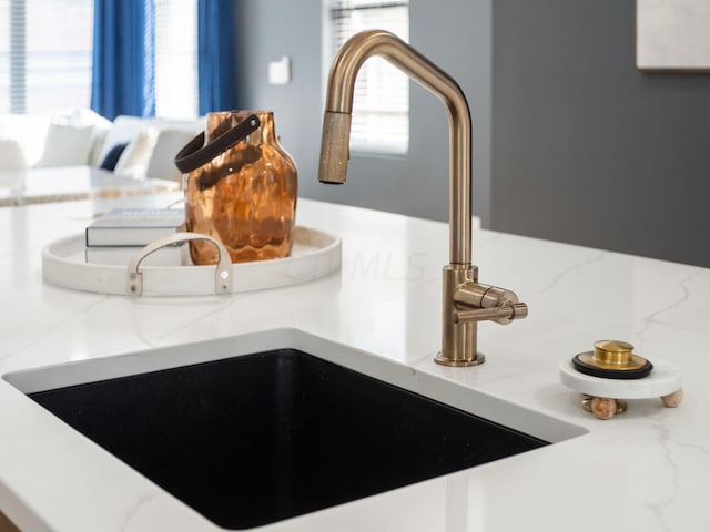 interior details featuring light stone counters, sink, and backsplash