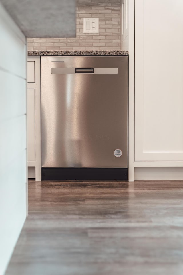 room details featuring dark hardwood / wood-style flooring, dishwasher, white cabinets, and dark stone counters